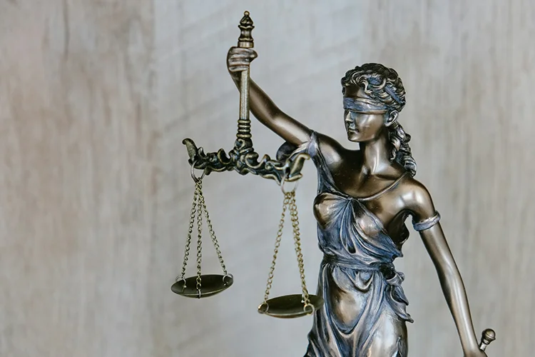 alt="Statue d'une femme tenant une balance de justice dans la main droite"