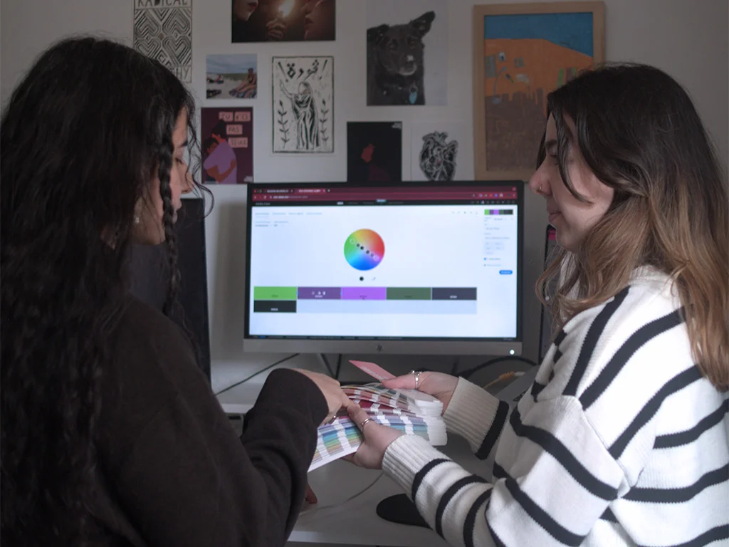 Graphiste & DA My Meraki Design, discutant avec une cliente, ayant un Pantone nuancier dans la main.
